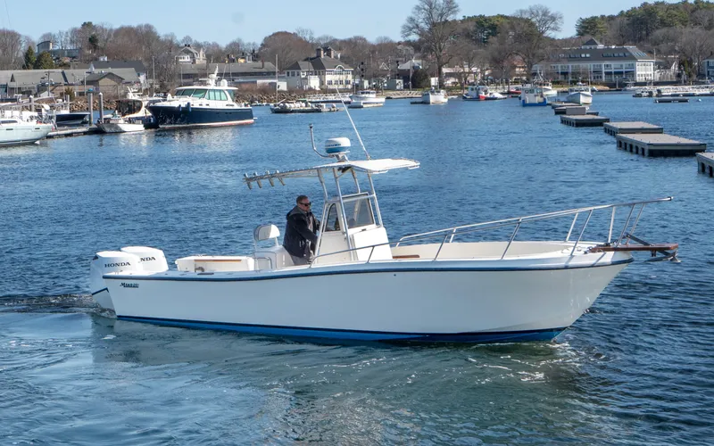 Slide: The Image of 1990 Mako 261 Center Console boat cruising in a scenic harbor. - 7