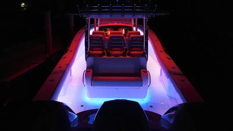 Slide: The Image of 2026 Mag Bay 43 CC boat with vibrant red and blue interior lighting at night. - 7