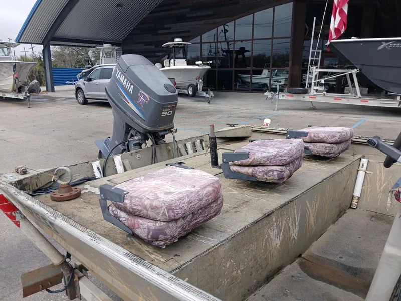 Slide: The Image of 2004 Xpress 18 boat with Yamaha 90 engine, camo seats, parked at a dealership. - 4