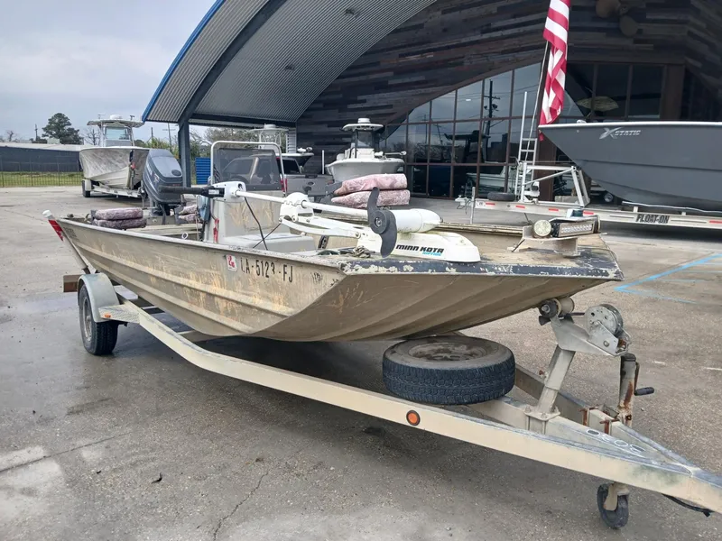 Slide: The Image of 2004 Xpress 18 boat on trailer, parked outdoors near a modern building. - 7