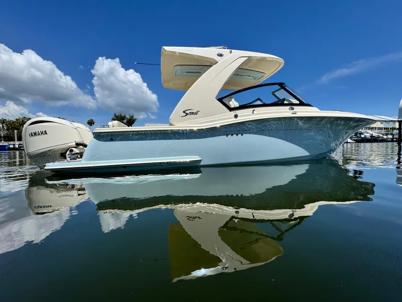 Slide: The Image of 2025 Scout 277 Dorado boat on calm water with Yamaha engine, under clear blue sky. - 1