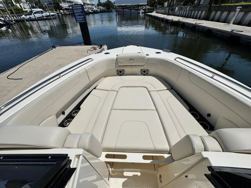 Slide: The Image of 2025 Scout 277 Dorado boat interior with luxurious seating at a marina dock. - 21