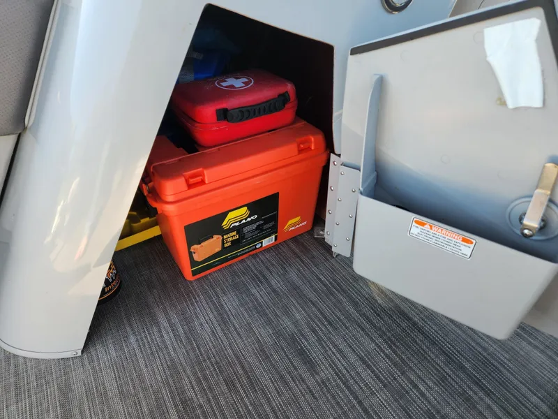 Slide: The Image of Storage compartment in a 2021 Bennington SX 21 L-Bench with safety gear and equipment. - 22
