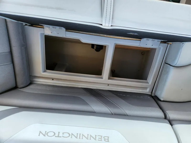 Slide: The Image of 2021 Bennington SX 21 L-Bench storage compartment with open lid, showcasing interior space. - 25