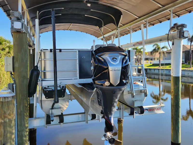 Slide: The Image of 2021 Bennington SX 21 L-Bench pontoon boat on lift in sunny marina. - 3