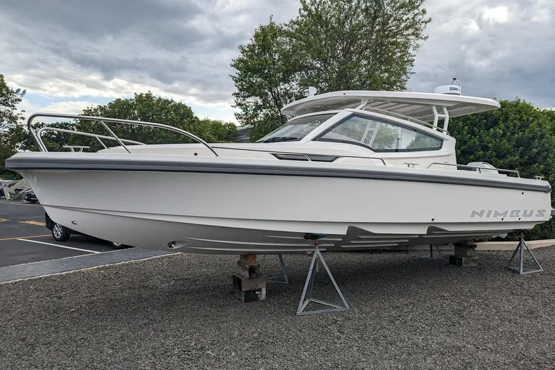 Slide: The Image of 2025 Nimbus Weekender 9 boat on display, white hull, sleek design, parked outdoors. - 1