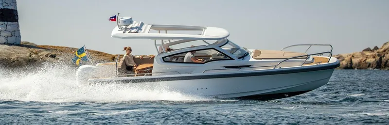 Slide: The Image of 2025 Nimbus Weekender 9 cruising on open water near rocky shoreline. - 11