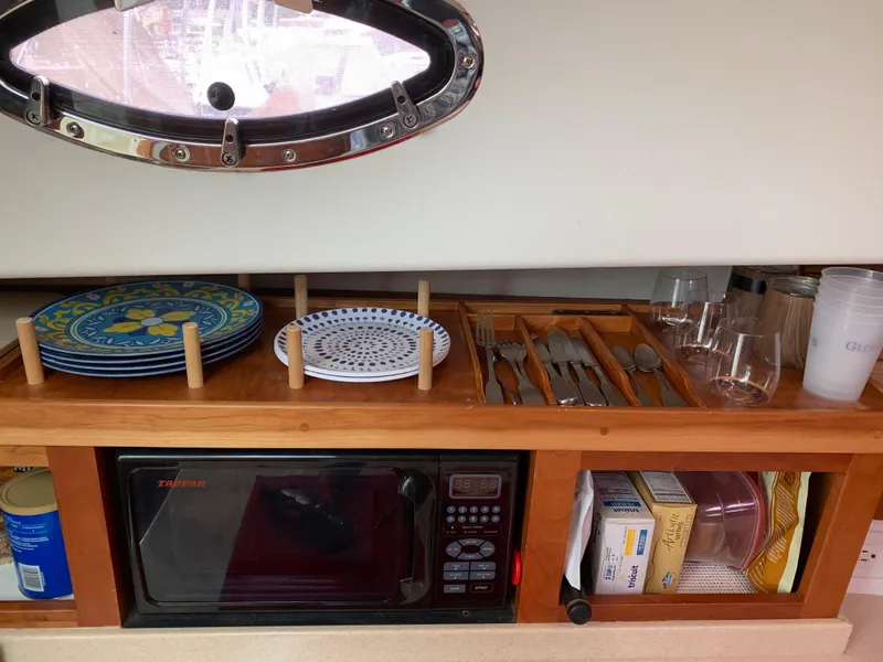 Slide: The Image of 2006 Back Cove Hardtop Express galley with microwave, plates, utensils, and glassware storage. - 10