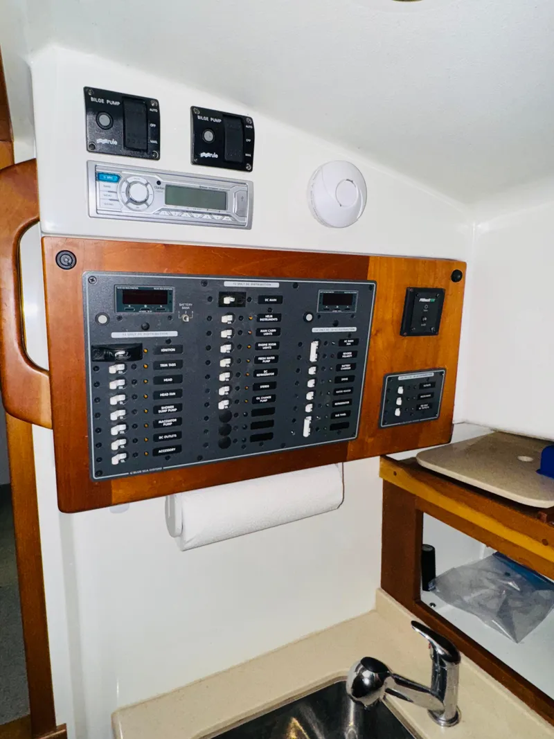 Slide: The Image of Electrical panel inside 2006 Back Cove Hardtop Express boat, featuring control switches and stereo system. - 11