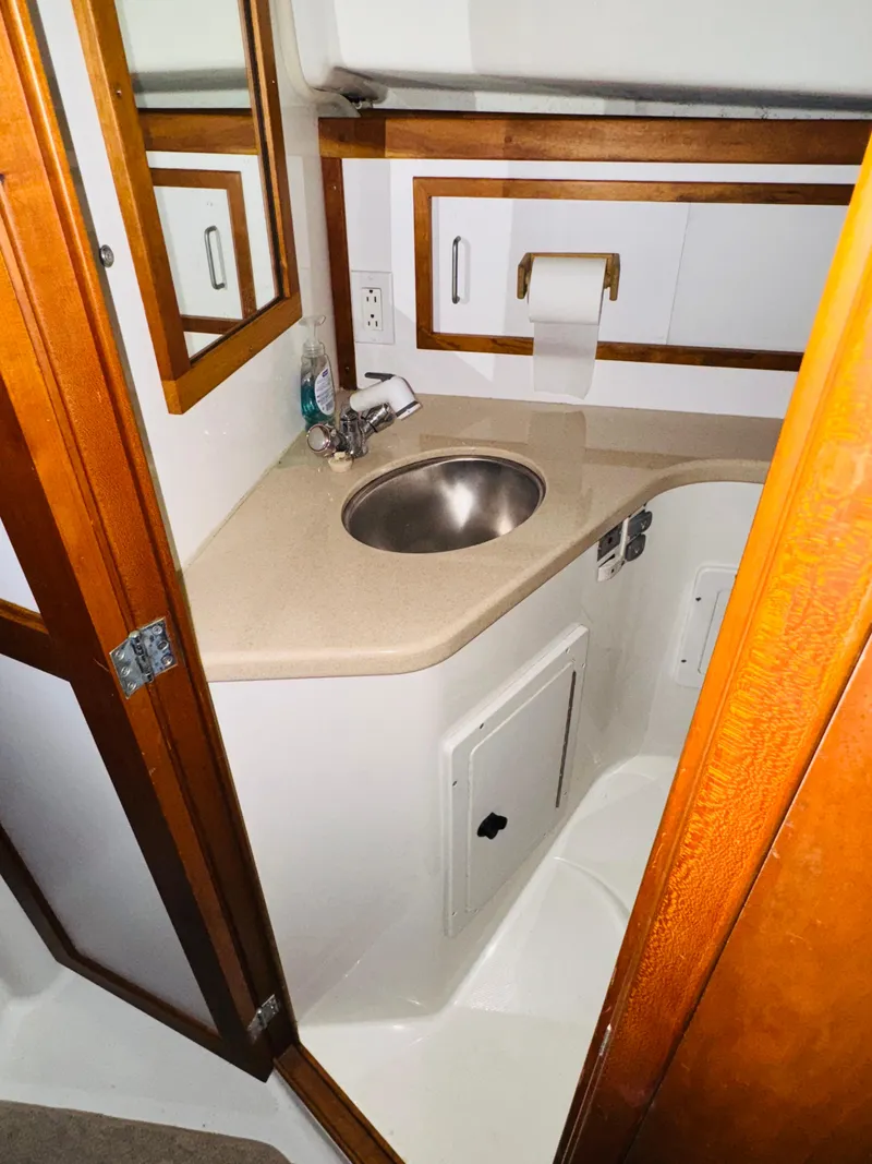 Slide: The Image of 2006 Back Cove Hardtop Express bathroom with sink, mirror, and wooden accents. - 14
