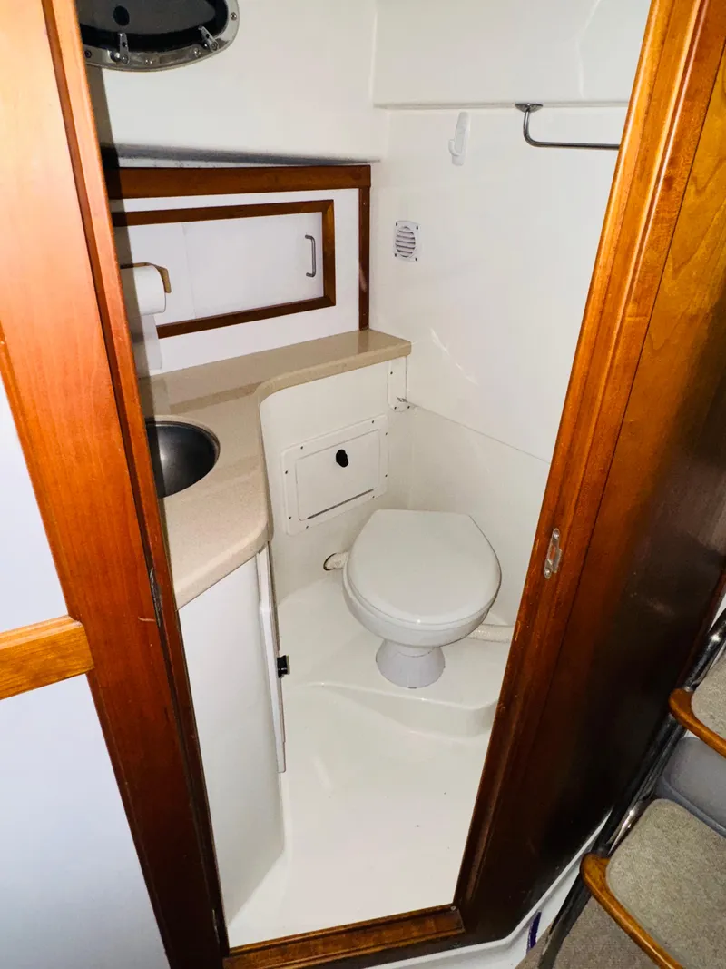 Slide: The Image of 2006 Back Cove Hardtop Express bathroom with sink, toilet, and wooden cabinetry. - 15