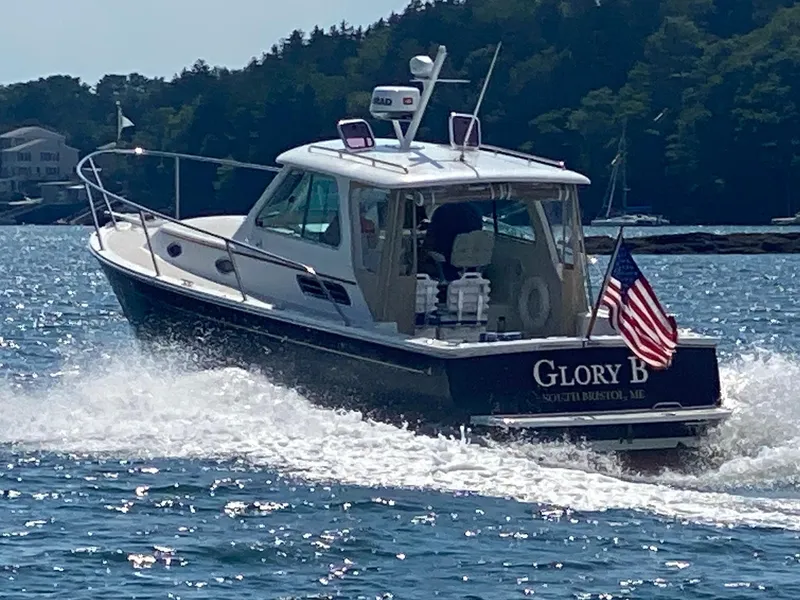 Slide: The Image of 2006 Back Cove Hardtop Express boat cruising on water with American flag. - 2