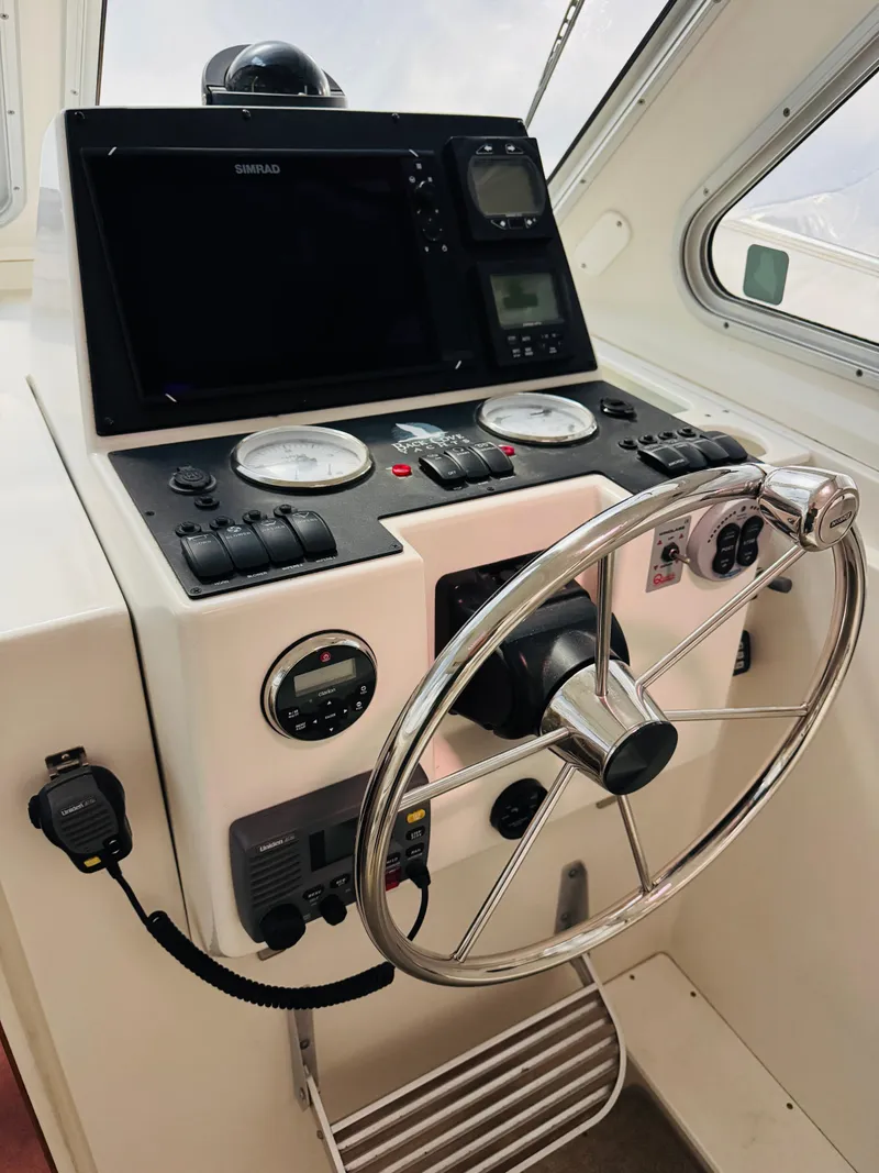 Slide: The Image of 2006 Back Cove Hardtop Express helm with steering wheel and navigation instruments. - 3