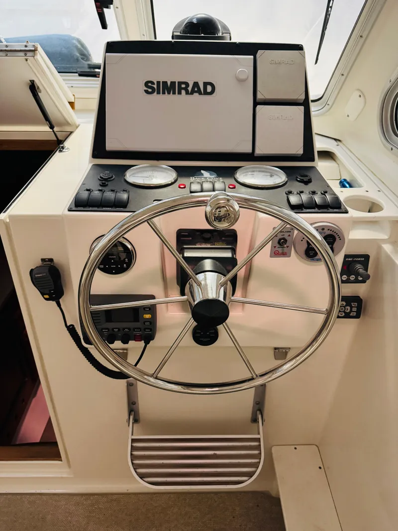 Slide: The Image of 2006 Back Cove Hardtop Express helm with Simrad navigation system and steering wheel. - 4