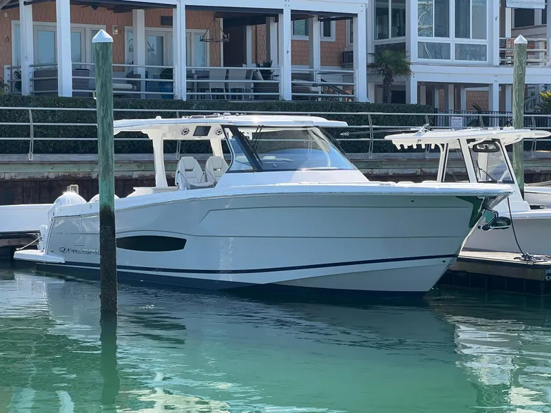 Slide: The Image of 2025 Regal 38 SAV boat cruising on a calm, sunny waterway. - 0