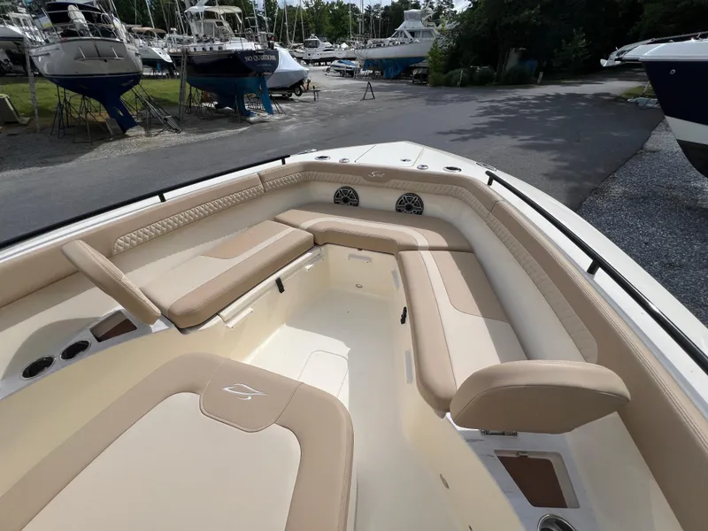 Slide: The Image of 2025 Scout 260 LXF boat interior with beige seating in a marina setting. - 6