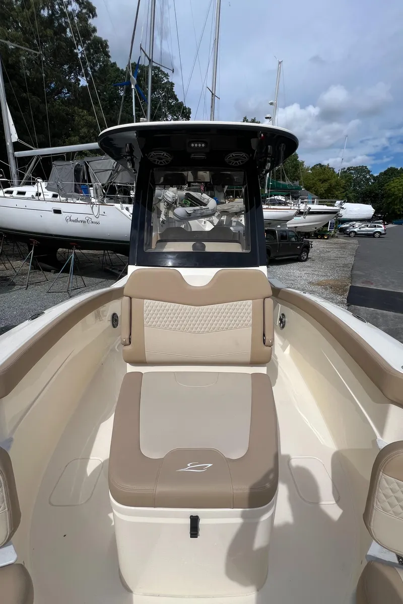 Slide: The Image of 2025 Scout 260 LXF boat interior with beige seating, docked near sailboats. - 8
