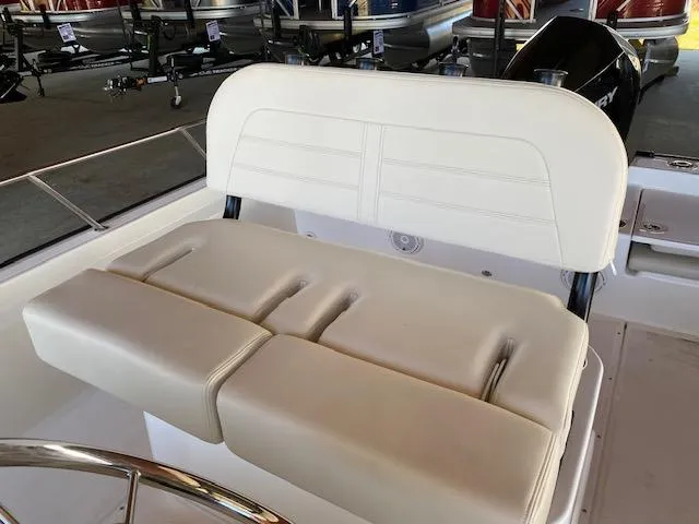 Slide: The Image of 2025 Boston Whaler 210 Montauk boat seat, white upholstery, in a showroom setting. - 5