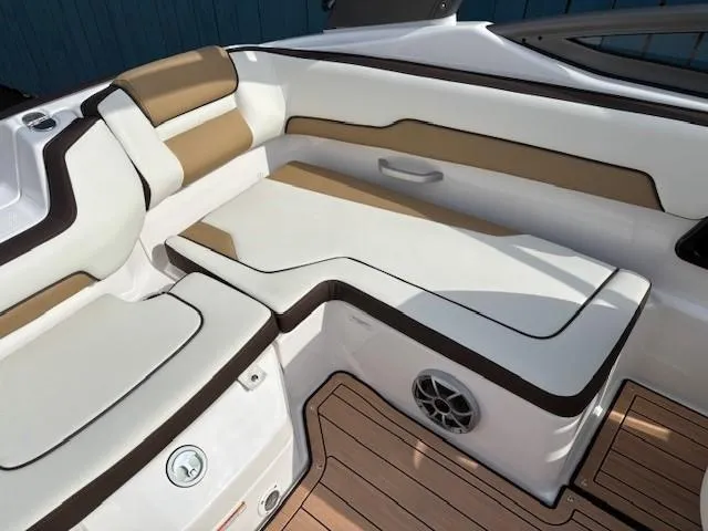 Slide: The Image of 2021 Yamaha Boats 195S interior seating with tan and white upholstery, featuring a built-in speaker. - 23
