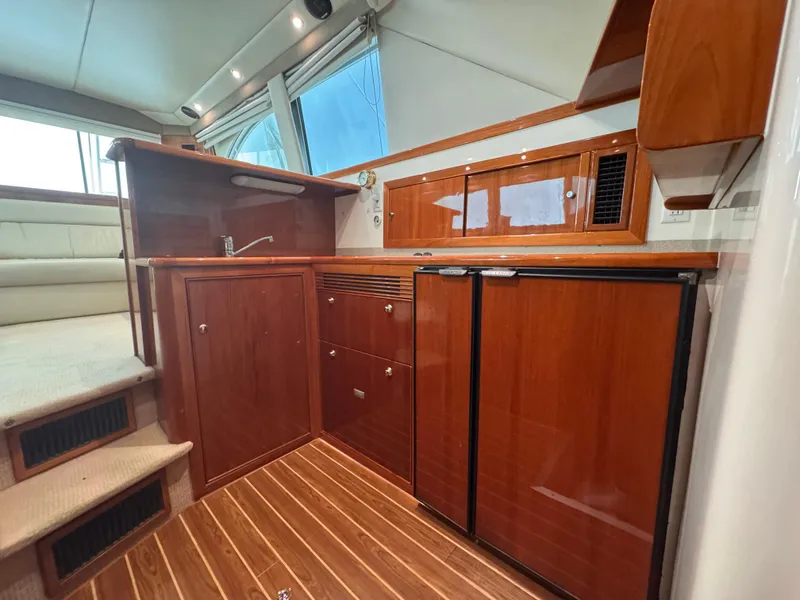 Slide: The Image of Interior of 2005 Riviera 40 Flybridge yacht with wooden cabinetry and compact kitchen area. - 12