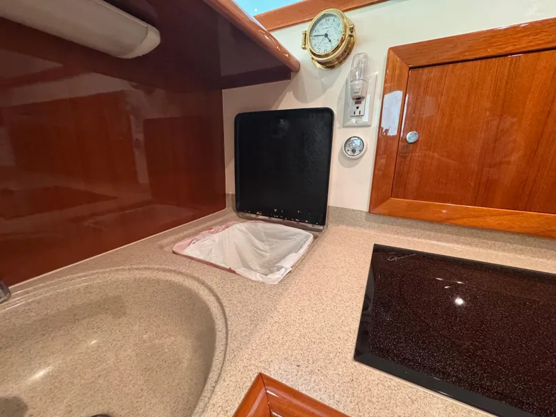 Slide: The Image of 2005 Riviera 40 Flybridge kitchen with sink, stove, and wooden cabinetry. - 14
