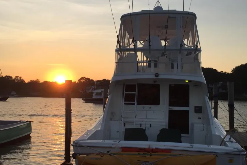 Slide: The Image of Riviera 40 Flybridge 2005 yacht docked at sunset, serene waterfront view. - 2