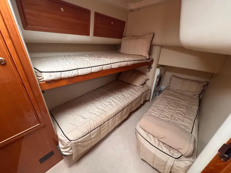 Slide: The Image of 2005 Riviera 40 Flybridge cabin with three cozy bunk beds and wooden storage cabinets. - 22