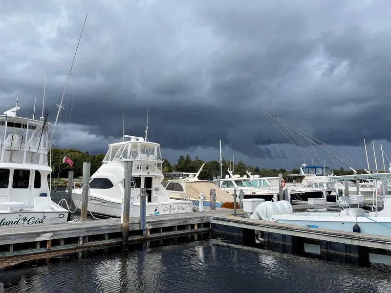 Slide: The Image of Boats docked at marina under stormy skies, featuring a 2005 Riviera 40 Flybridge. - 3