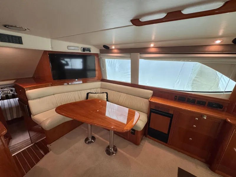 Slide: The Image of 2005 Riviera 40 Flybridge interior with plush seating, wooden table, and built-in TV. - 6