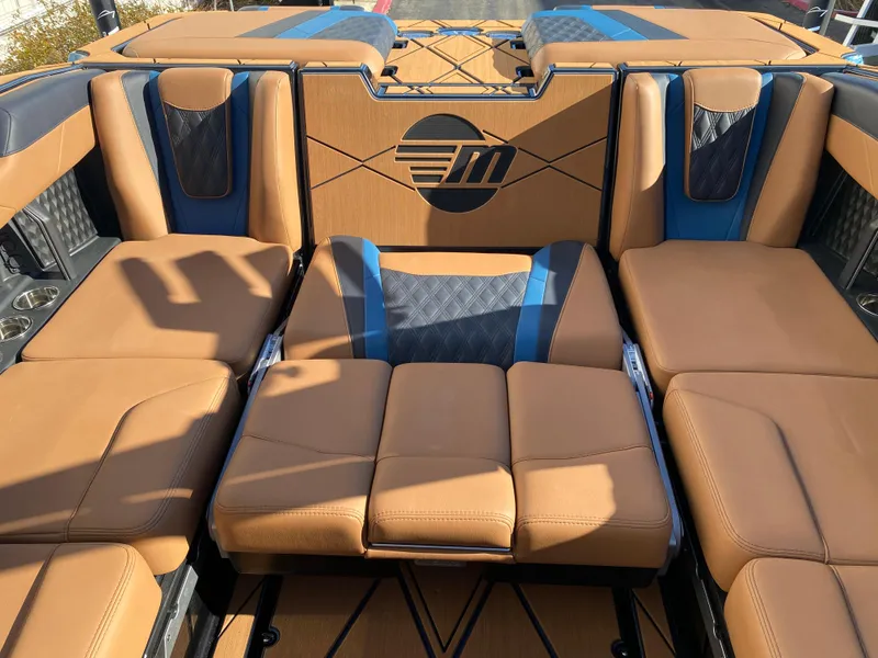 Slide: The Image of 2025 Malibu M230 boat interior with tan and blue seating, featuring a stylish design. - 15