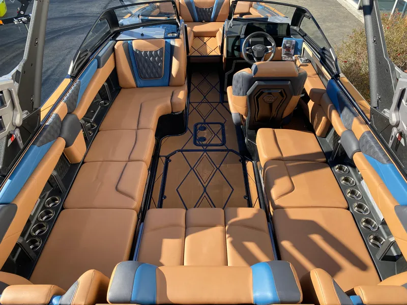 Slide: The Image of 2025 Malibu M230 boat interior with luxurious tan and blue seating, modern design. - 16