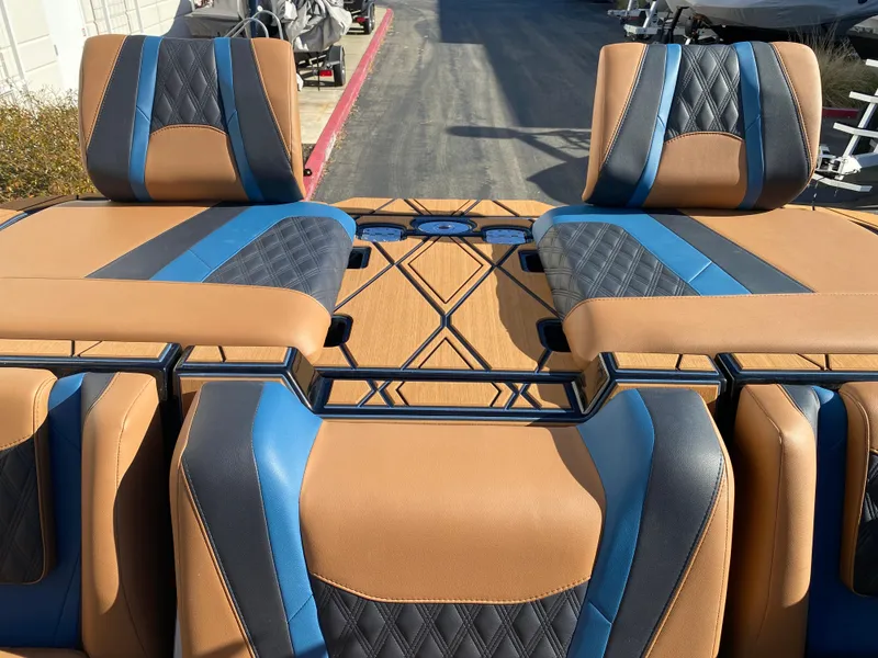 Slide: The Image of 2025 Malibu M230 boat interior with tan and blue upholstery, featuring diamond stitching. - 17