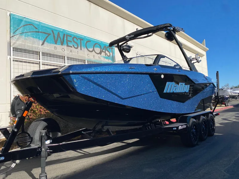 Slide: The Image of 2025 Malibu M230 boat in blue, displayed at West Coast Boat Center. - 2