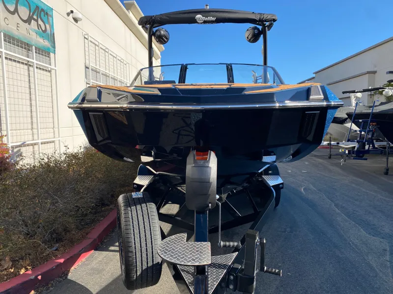 Slide: The Image of 2025 Malibu M230 boat on trailer, parked outdoors, front view. - 22