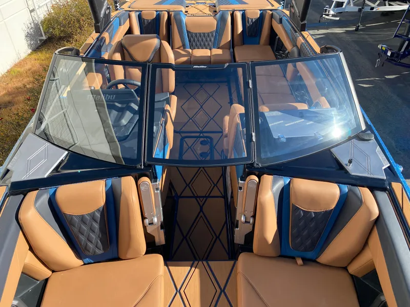Slide: The Image of 2025 Malibu M230 boat interior with tan and blue seating, modern design, and spacious layout. - 23