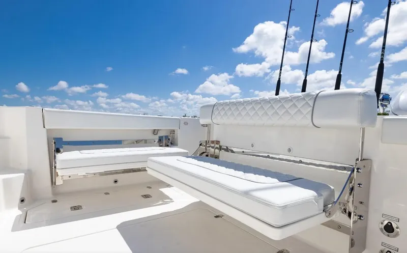 Slide: The Image of 2025 Pursuit OS 325 boat deck with white seating and fishing rods under a clear blue sky. - 16