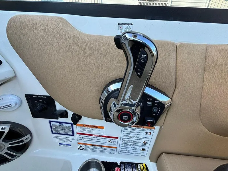 Slide: The Image of 2025 Sea Ray SDX 270 Outboard throttle control with warning labels and cup holder. - 13