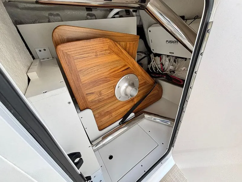 Slide: The Image of Storage compartment in a 2025 Sea Ray SDX 270 Outboard boat with wooden table and Fusion audio system. - 18