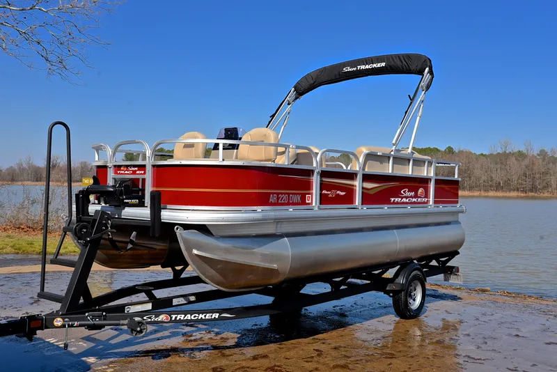 Slide: The Image of 2022 Sun Tracker BASS BUGGY 18 pontoon boat on trailer by a lake. - 10