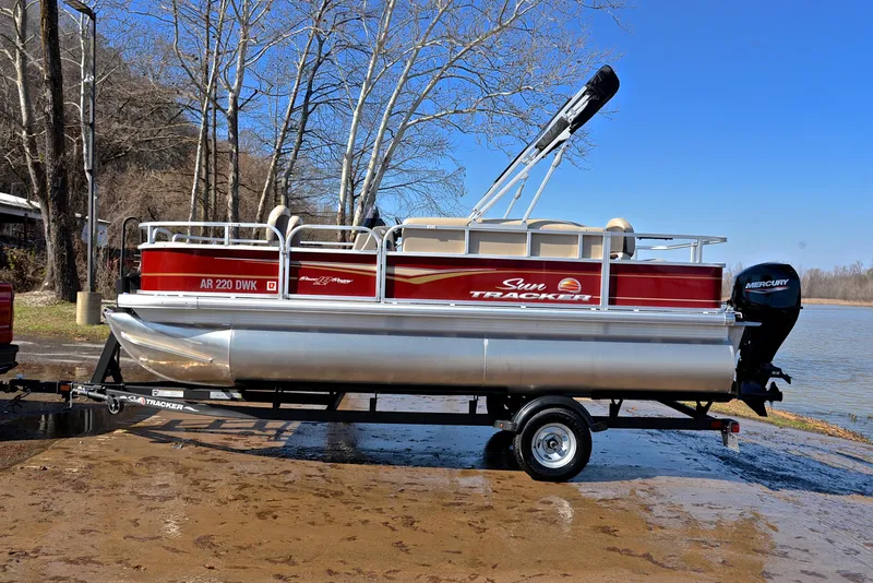 Slide: The Image of 2022 Sun Tracker BASS BUGGY 18 pontoon boat on trailer by a lake. - 11