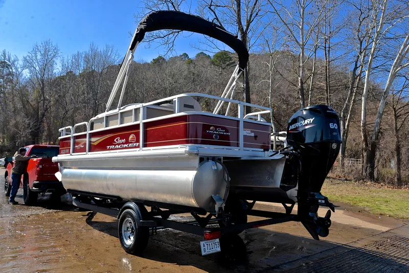 Slide: The Image of 2022 Sun Tracker BASS BUGGY 18 pontoon boat on trailer near wooded area. - 12