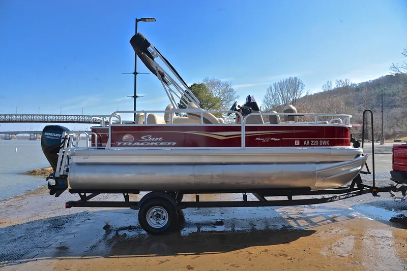 Slide: The Image of 2022 Sun Tracker BASS BUGGY 18 pontoon boat on trailer by riverside. - 15