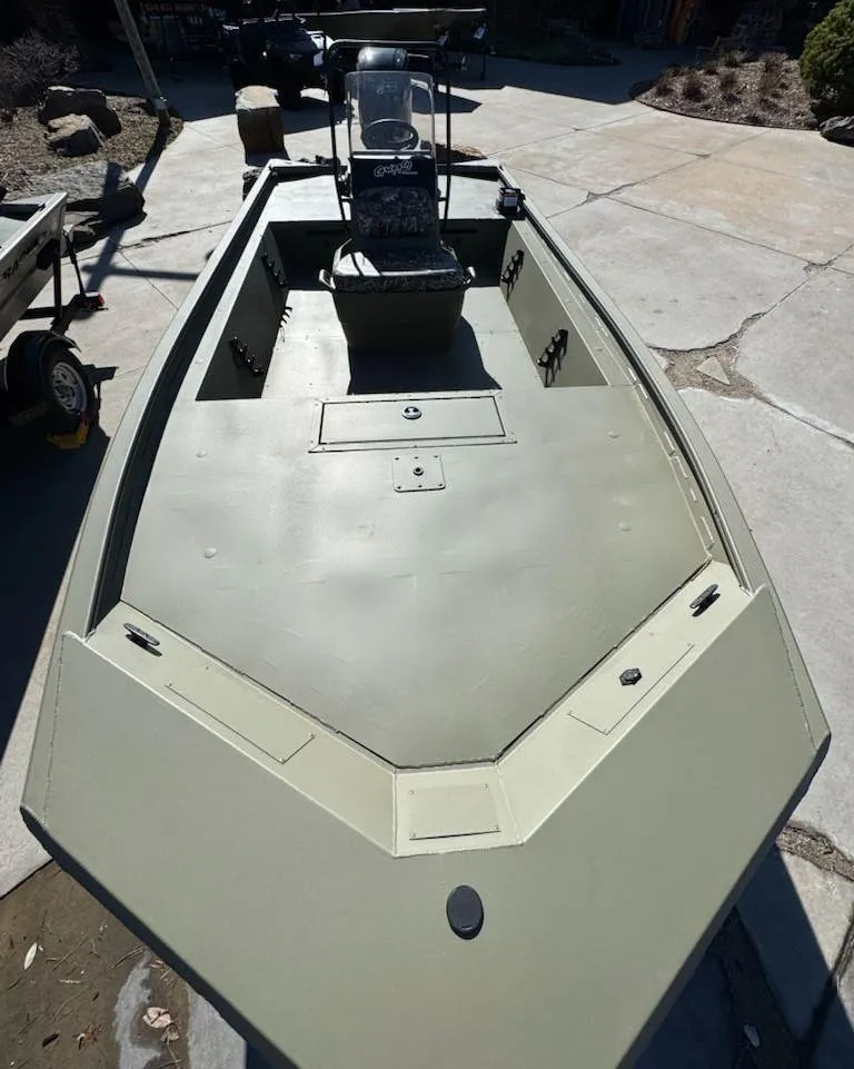 Slide: The Image of 2025 Tracker Grizzly 1860 CC boat, olive green, center console, parked on concrete. - 7