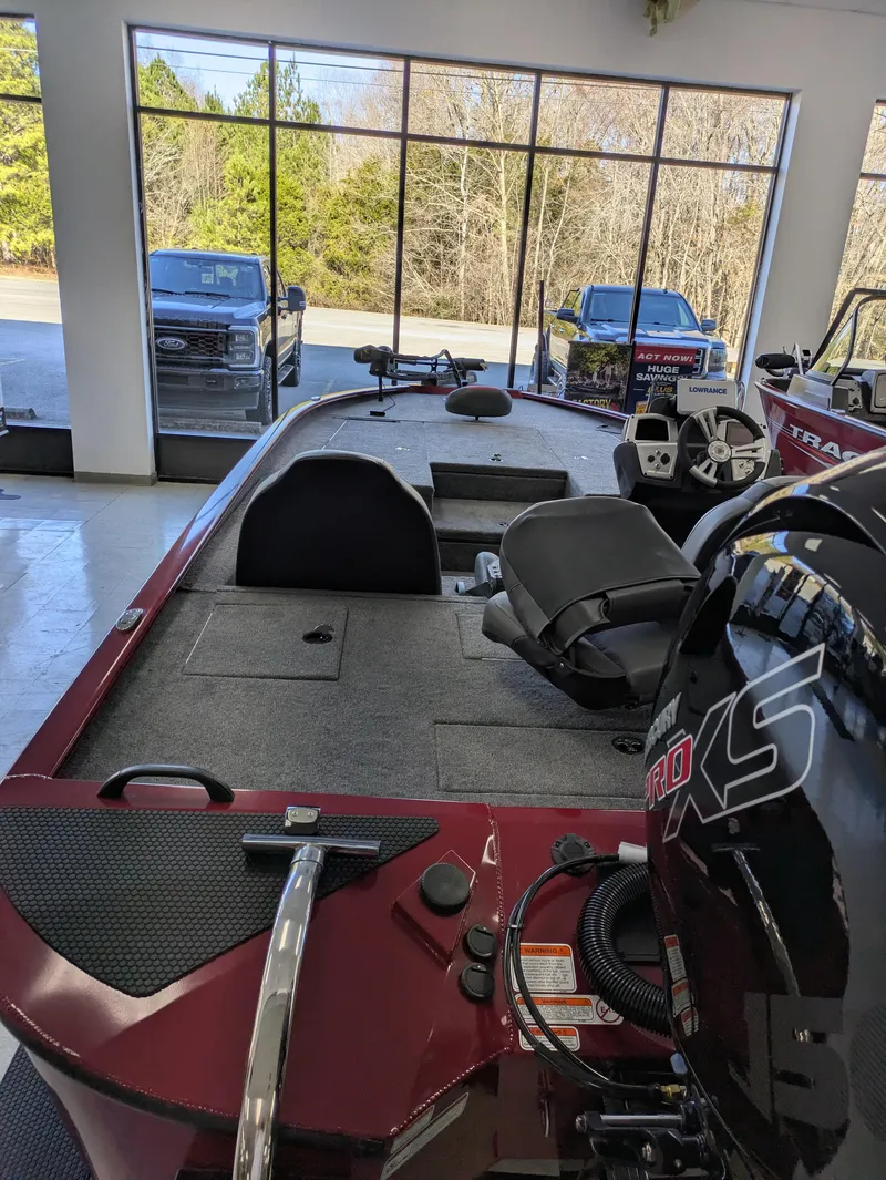 Slide: The Image of 2025 Tracker Savage 215 boat on trailer, parked outdoors with trees in background. - 2