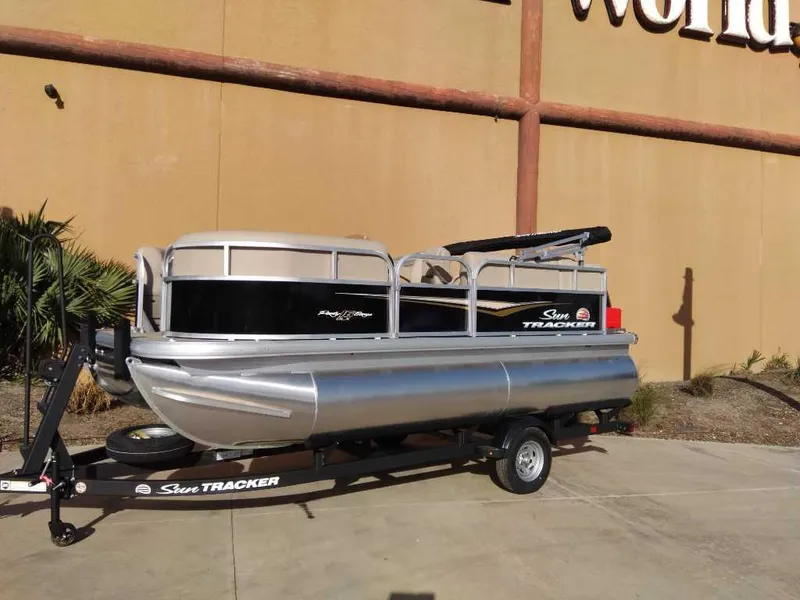 Slide: The Image of 2025 Sun Tracker Party Barge 16 DLX pontoon boat on trailer, parked outdoors. - 19