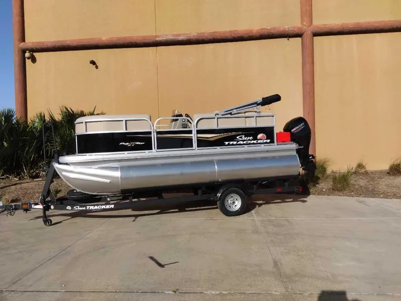 Slide: The Image of 2025 Sun Tracker Party Barge 16 DLX pontoon boat on trailer, outdoor setting. - 56