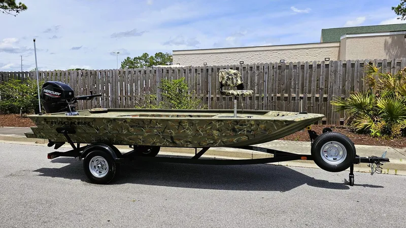 Slide: The Image of 2025 Tracker Grizzly 1654 T Sportsman boat on trailer, camo design, parked outdoors. - 4