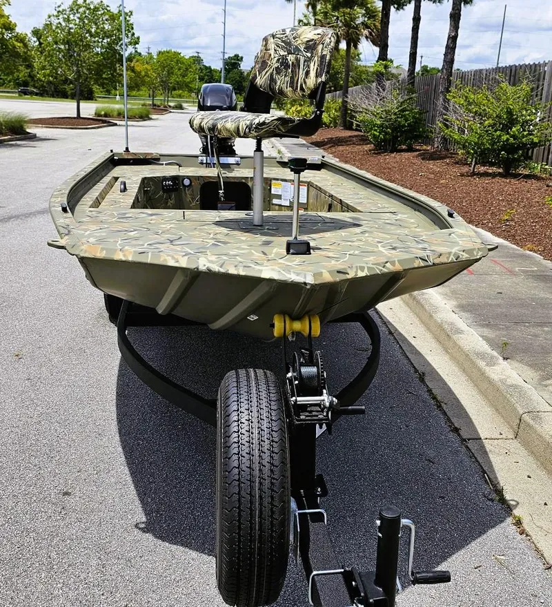 Slide: The Image of 2025 Tracker Grizzly 1654 T Sportsman boat on trailer, camo design, parked outdoors. - 6