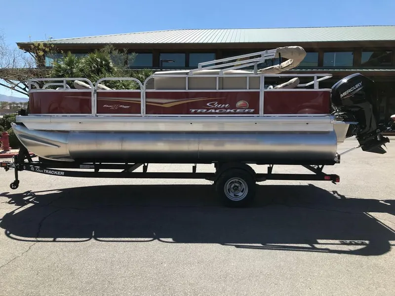 Slide: The Image of 2025 Sun Tracker Bass Buggy 18 DLX pontoon boat on trailer, parked outdoors. - 3