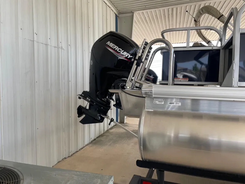 Slide: The Image of 2025 Sun Tracker Bass Buggy 18 DLX with Mercury outboard motor in a covered area. - 3